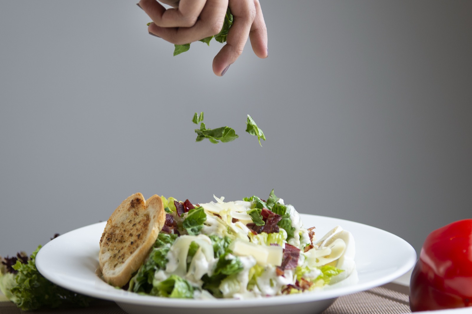 A chef finishing a salad with herbs