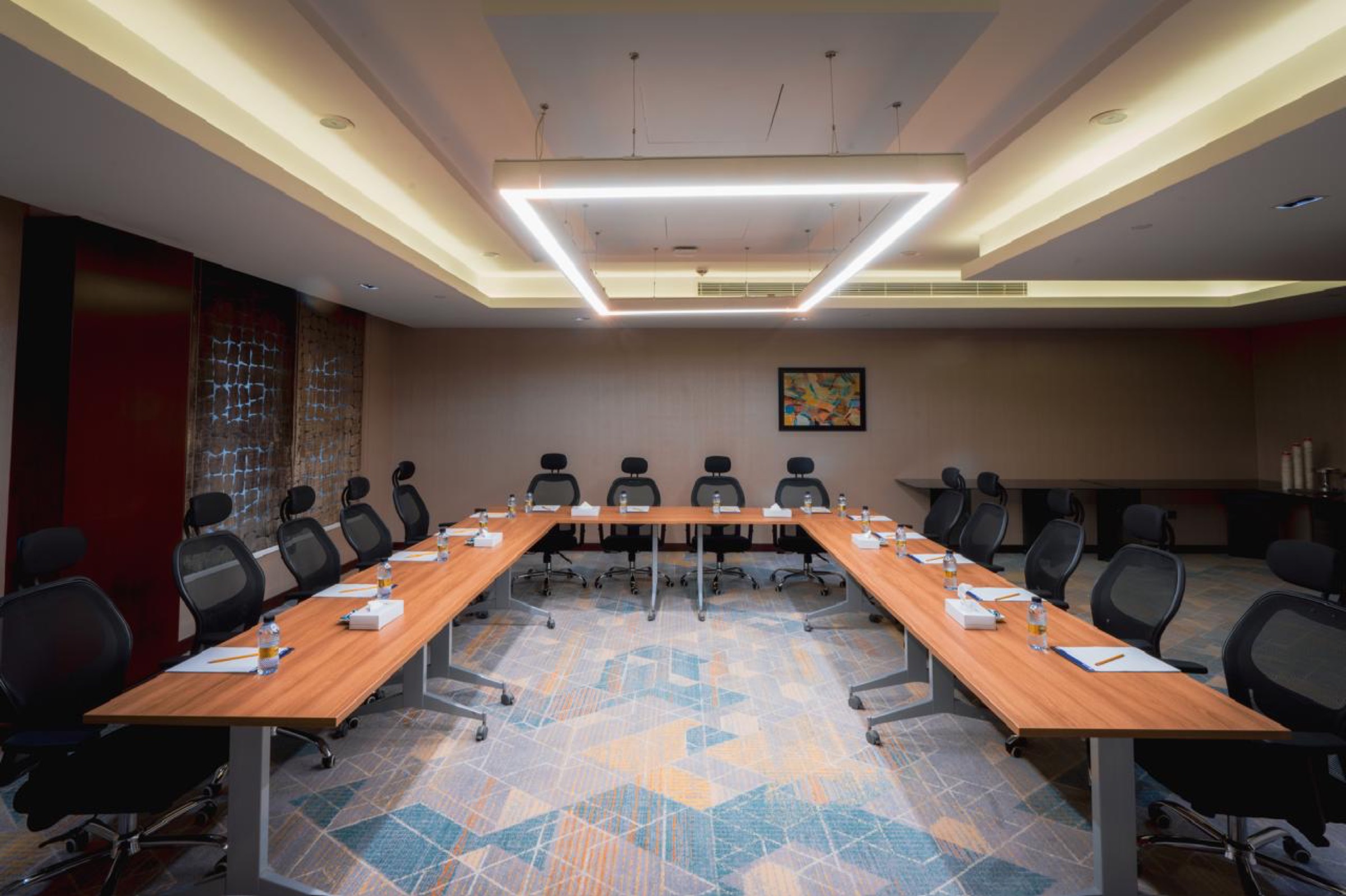 A meeting room set in a U-shape beneath a linear chandelier